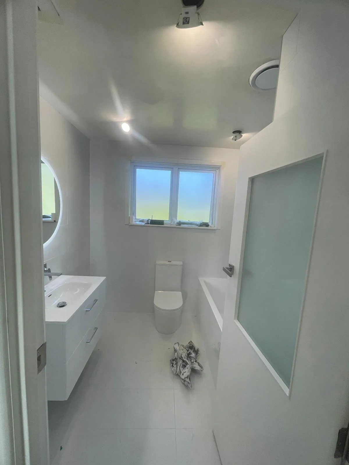 The same bathroom finished, with downlights, an extractor fan and a tiled shower