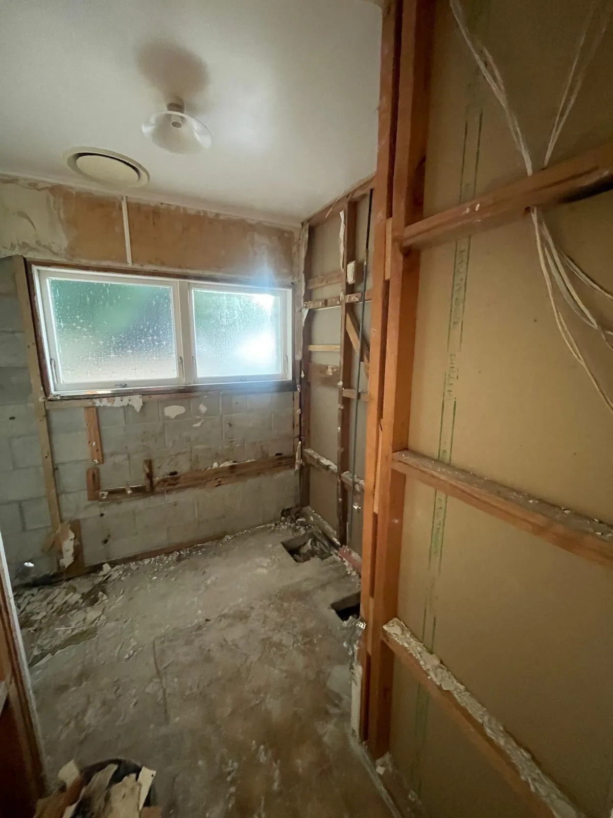 A bathroom stripped back to blockwork and framing, with the old lining and fittings taken out