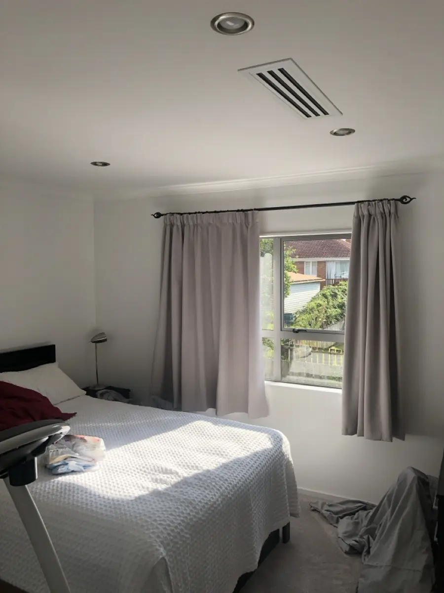 A ducted air conditioning outlet installed in a bedroom ceiling beside downlights