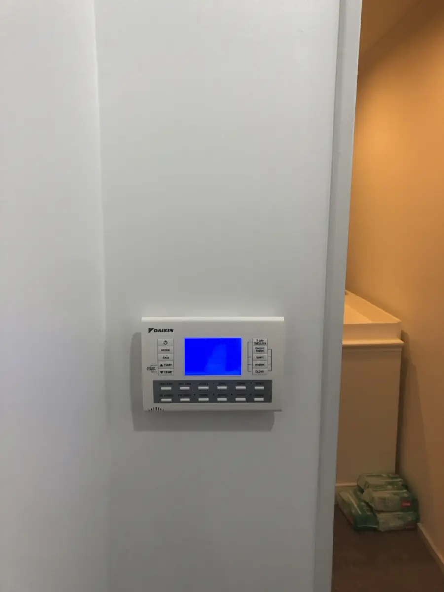 A Daikin ducted air conditioning wall controller mounted in a hallway