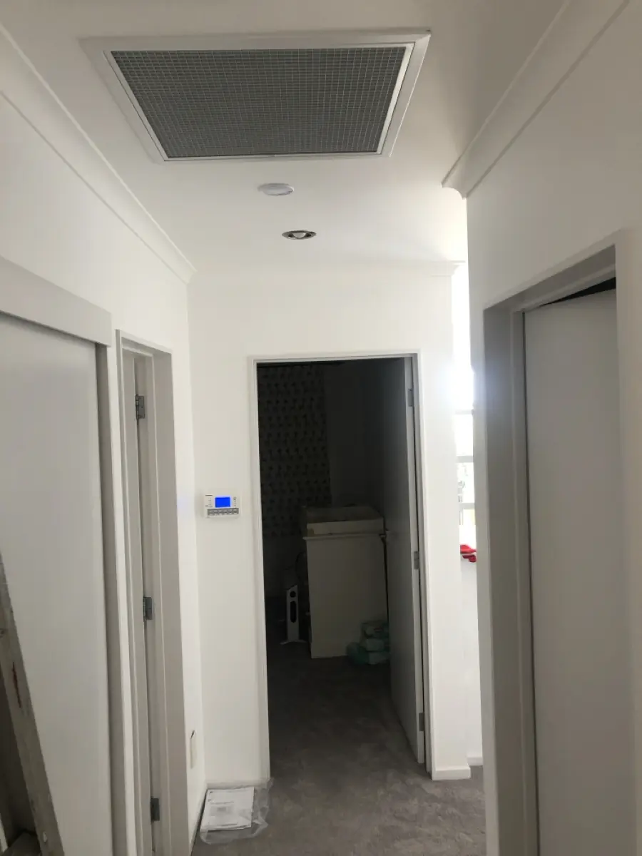 A ducted air conditioning return-air grille and wall controller in a hallway ceiling