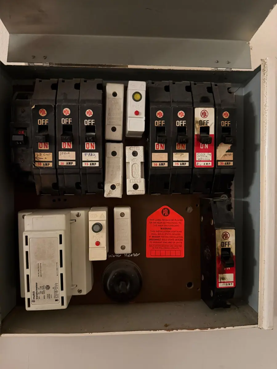 An old switchboard with plug-in fuse carriers labelled with handwritten amperage ratings