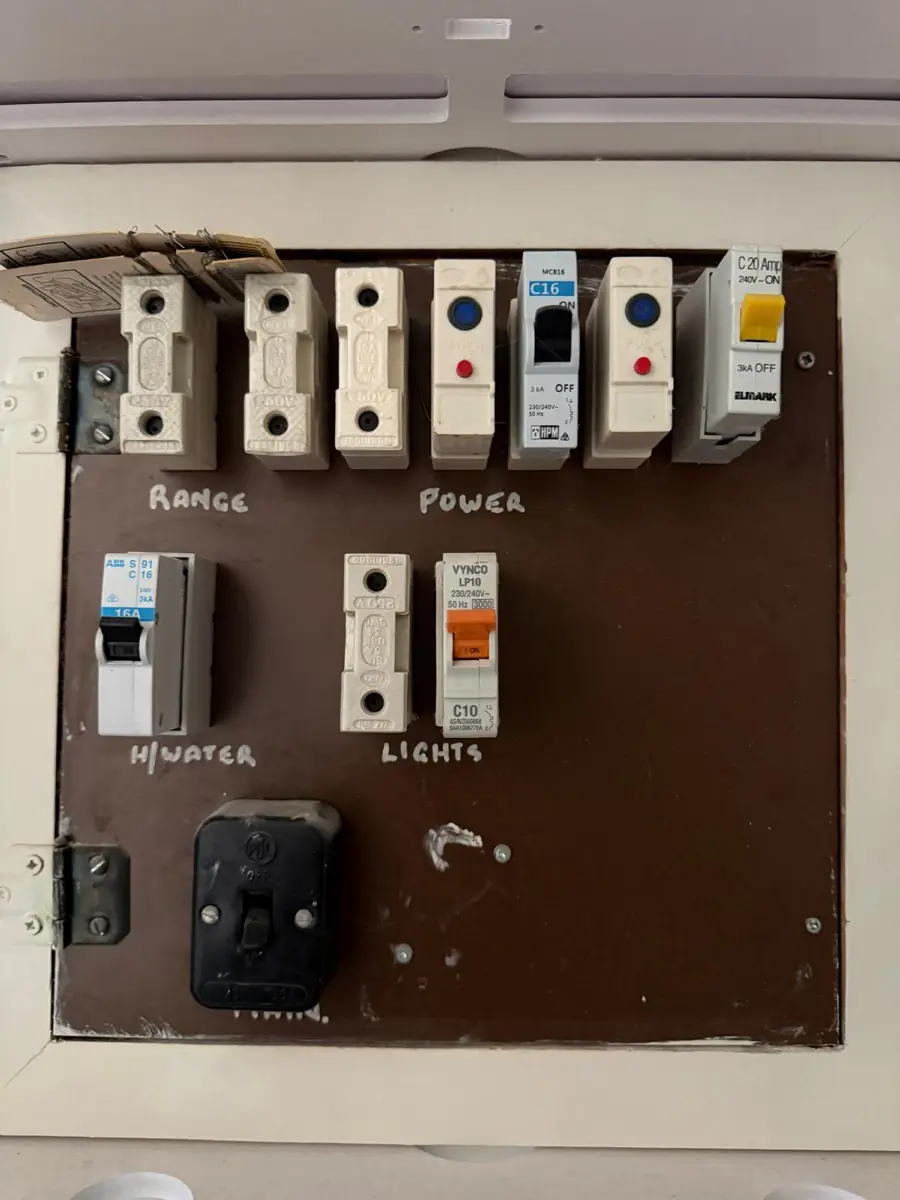 An old switchboard labelled Range, Power, Hot Water and Lights with ceramic fuses
