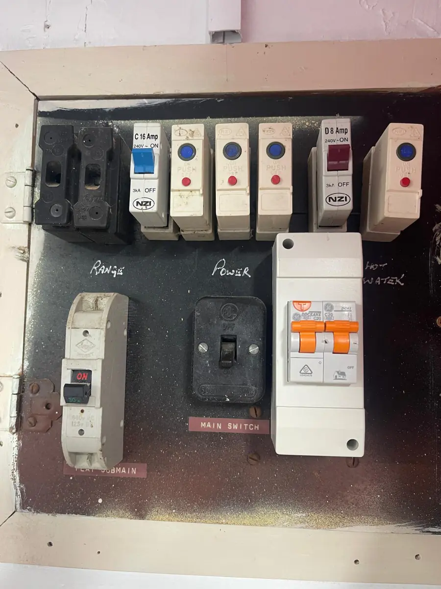 An old black switchboard with a single main switch and a later RCD added alongside the original fuses