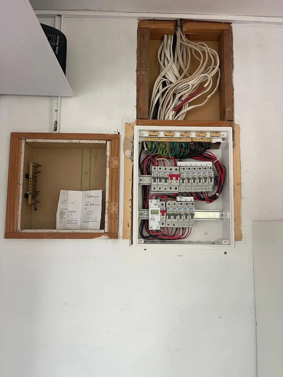 A new switchboard installed on the wall beside the empty cavity left by the old fuse box