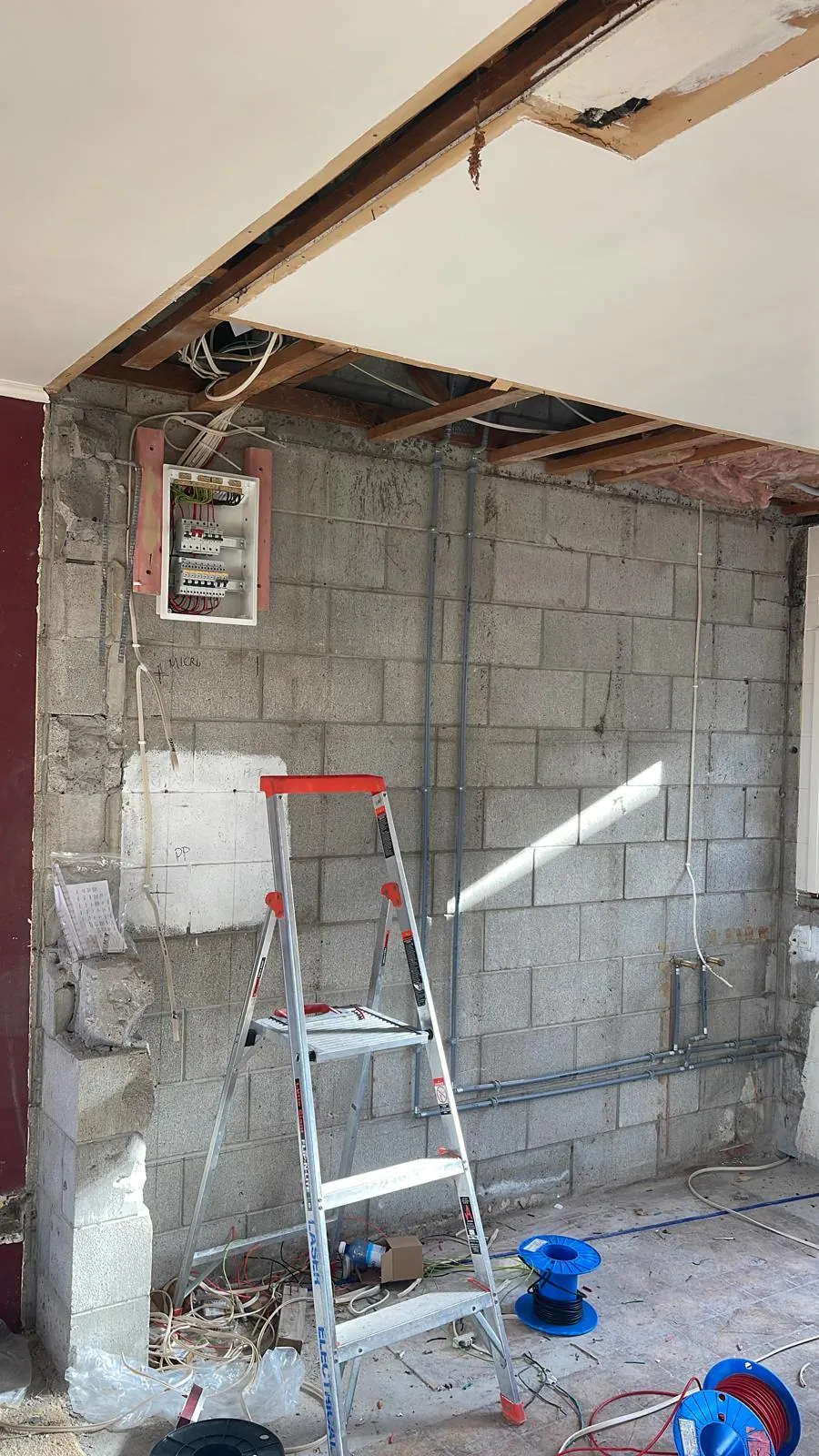 A new consumer unit mounted on a block wall with fresh conduit runs during a renovation